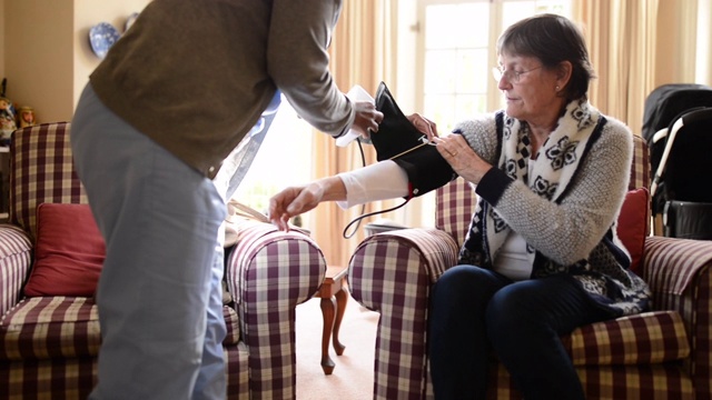 年轻护士在家给一位老年病人量血压视频素材