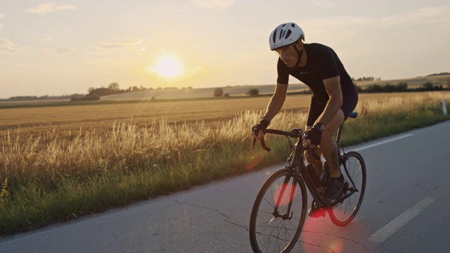 SLO MO专业自行车手在日落时快速通过乡村视频下载