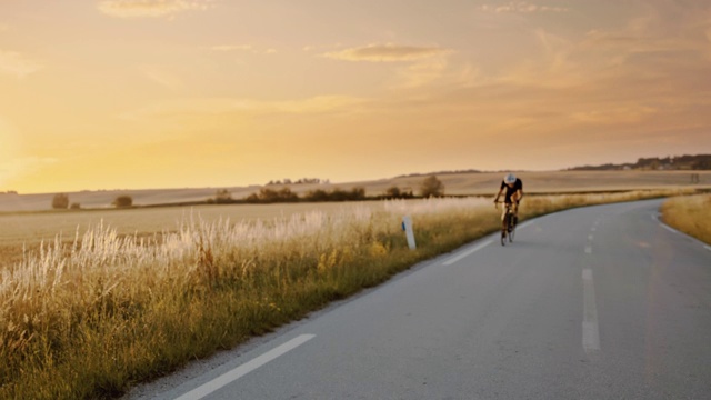 成人骑自行车在日落时快速穿过乡村视频素材