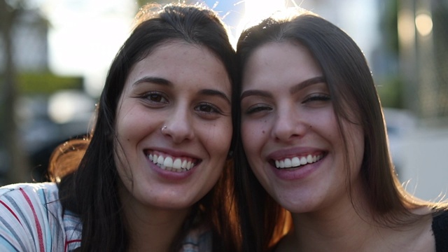 两个年轻女子对着镜头微笑。女孩真实生活的肖像微笑和大笑视频素材
