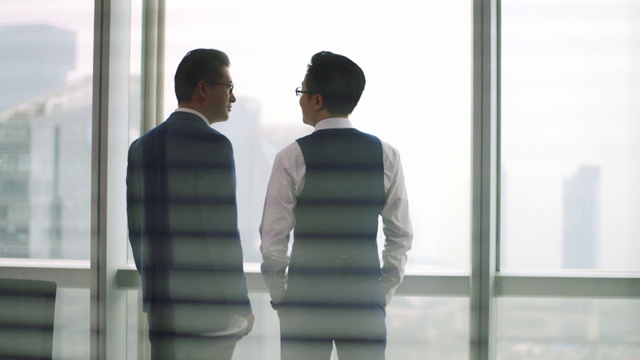 两个亚洲商人站在窗前聊天视频下载