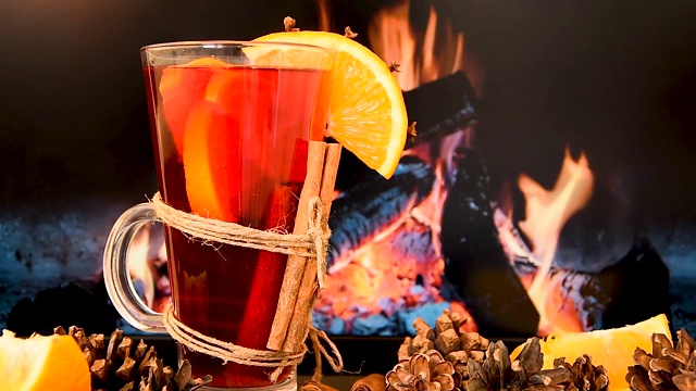 Cinemagraph -热葡萄酒杯与肉桂和橙色在桌子前燃烧的壁炉。运动的照片。视频素材