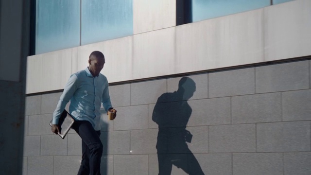 一位成功的非裔美国商人走在一家商业办公室附近的街道上视频素材