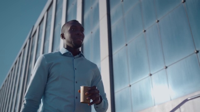 一位成功的非裔美国商人走在一家商业办公室附近的街道上视频素材