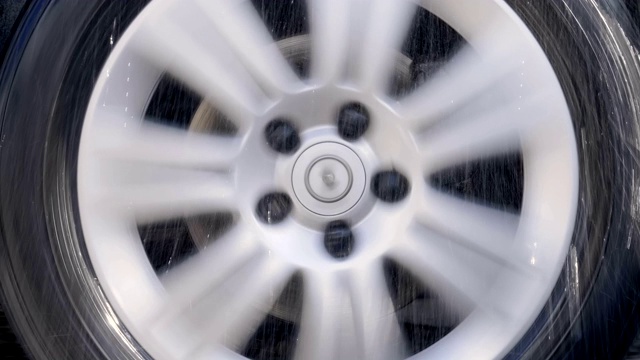 汽车的车轮带着闪亮的银色边缘，在雨点和强烈的摇晃中行驶视频素材