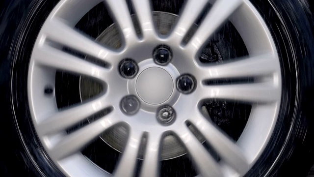 一个有着闪亮银色边缘的汽车轮子在糟糕的道路上摇晃视频素材