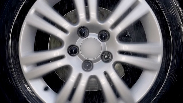一个有着闪亮银色边缘的汽车轮子在雨滴中行驶视频素材