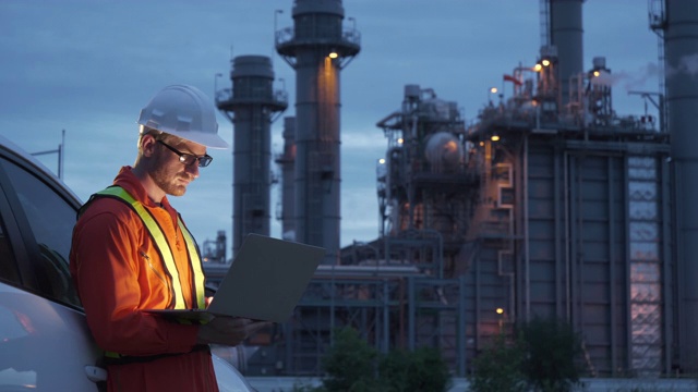 在工业园区的石油炼油厂，一名使用数字平板电脑的工程师夜班工作。化工、燃料发电、石化工厂行业概念视频素材