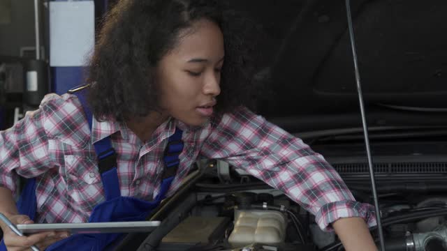 4K女汽车修理工在坡道上修理一辆汽车。视频素材