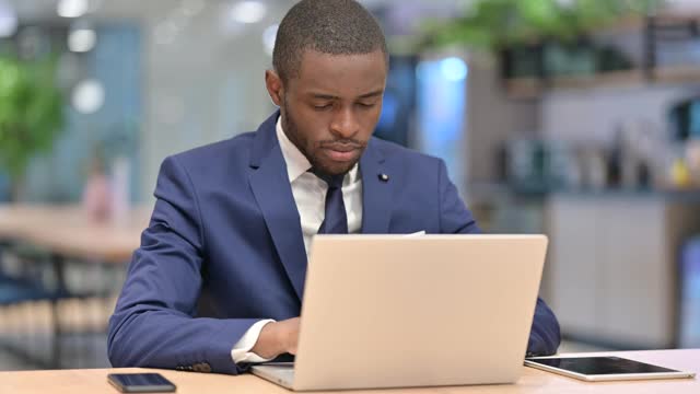 紧张的非洲商人与笔记本电脑头痛在办公室视频素材