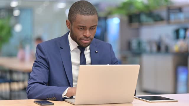 非洲商人用笔记本电脑在办公室里竖起大拇指视频素材