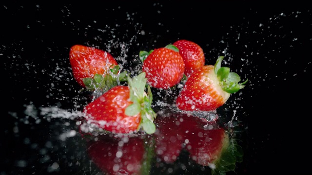 草莓落在潮湿的表面，溅起水滴视频素材