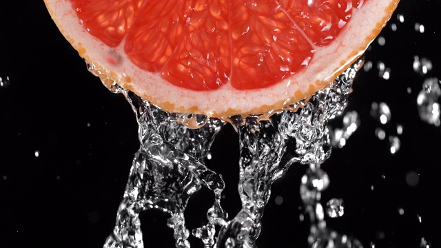水倒在背光多汁葡萄柚片上视频素材