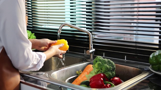 亚洲手妇女洗水果，橘子和准备健康的食物在厨房。视频素材