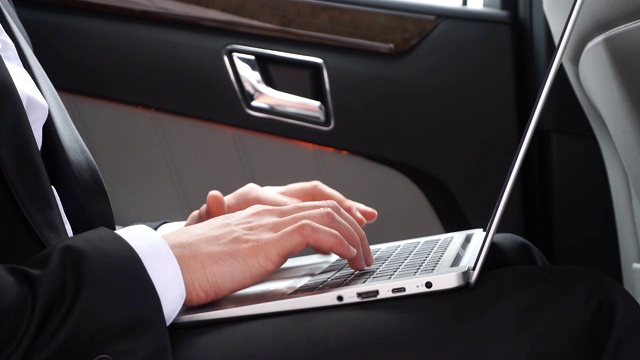 男性在正式的穿着与笔记本电脑在豪华轿车的特写视频下载