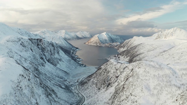 挪威Senja岛Medby附近积雪覆盖的山脉的航拍图。视频购买