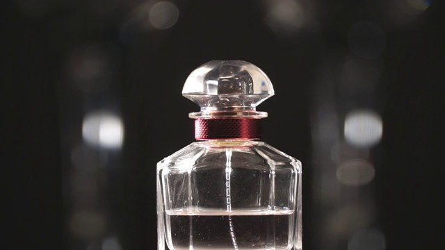 对一瓶奢侈香水的看法与它的光反射。模糊的背景。慢镜头视频素材