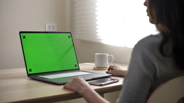 亚洲女人看着绿色屏幕的笔记本电脑视频素材