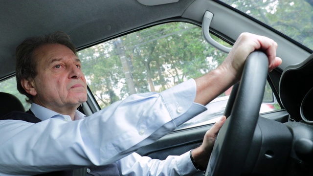 老人开车，握着方向盘在路上等待视频素材