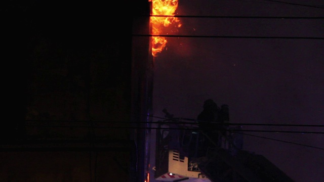 建筑在完全燃烧的地狱，消防队员争取控制火焰。消防队员把水流注入燃烧的房屋。视频素材