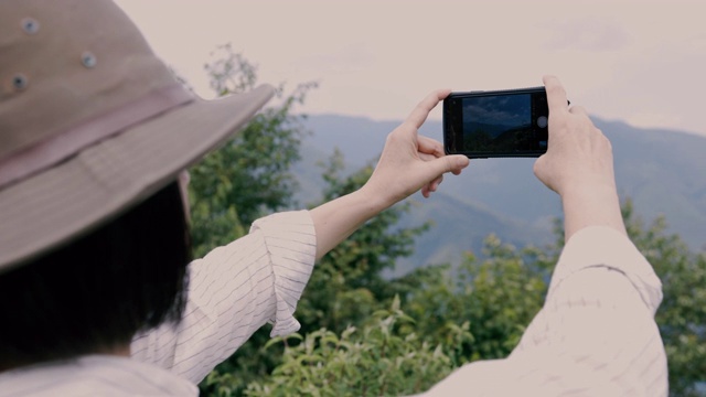 一位资深女性用智能手机拍摄风景的特写视频下载