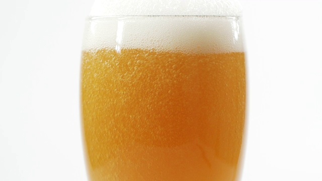 特写把啤酒倒进白色背景的杯子里视频素材