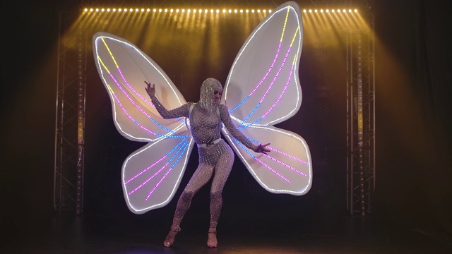 一位迷人的女子，身后是一只白色翅膀的蝴蝶，在舞台上唱歌。慢动作视频下载