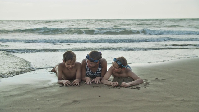 兄弟姐妹躺在沙滩上玩视频素材