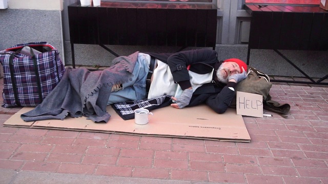 绝望的乞丐穿着旧衣服躺在纸板箱上要钱，任何帮助视频下载