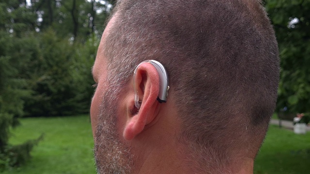 一名40岁的失聪男性在耳朵里戴着一个技术先进的助听器视频下载