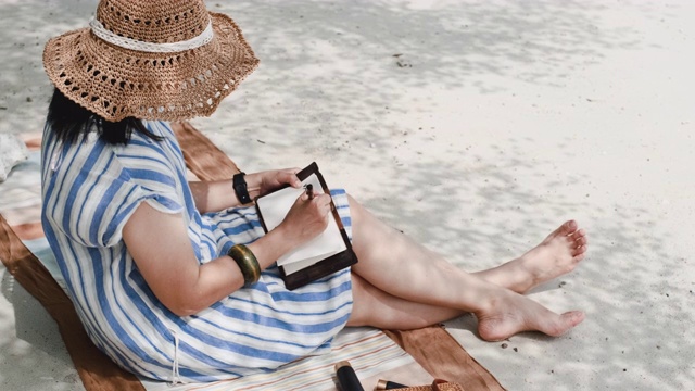 亚洲女人写新年决议明年坐在海滩上的暑假时间视频素材