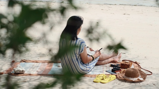 亚洲女人写新年决议明年坐在海滩上的暑假时间视频素材