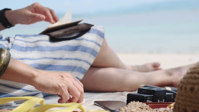 近距离的女人计划在笔记本上的新年目标和使用耳机听粘液在暑假时间在海滩上视频素材