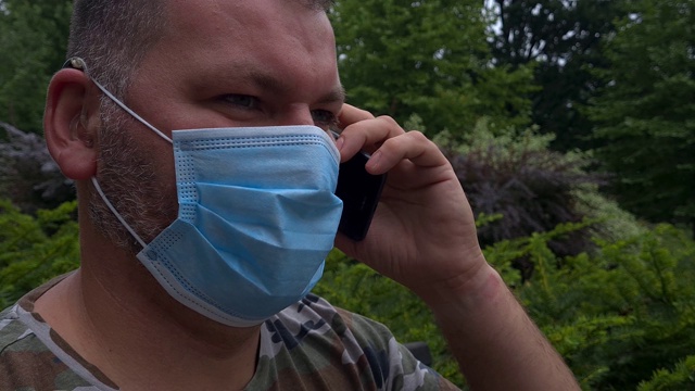 一名40岁男子戴着口罩在公园里打电话视频素材
