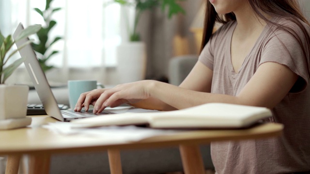 女性的手，商业女性专业用户工作者使用笔记本电脑打字，笔记本键盘，坐在家里的办公桌上在线工作视频素材