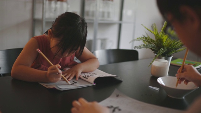 2个孩子在家学习写中国书法在餐厅视频素材