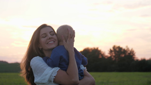 日落时分，快乐的妈妈带着孩子在田野里旋转视频素材