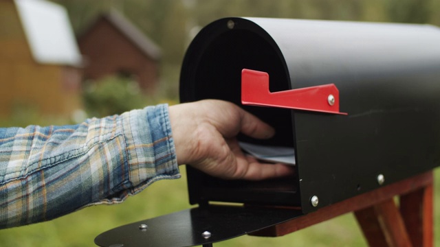 一个男人的手把信和选票投进他家附近的邮箱的特写视频下载