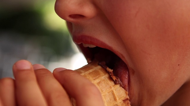 孩子嘴里吃着冰淇淋。特写的孩子在吃冰淇淋视频素材