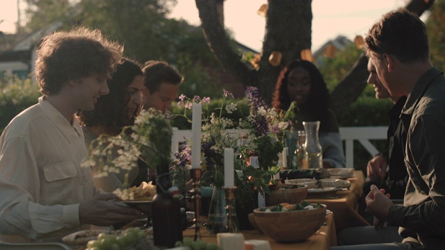手持式拍摄的朋友享受由桌子在花园派对视频素材