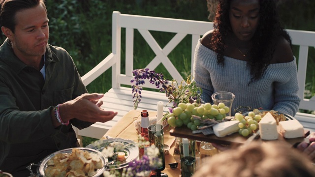 高角度的人给予切板与葡萄和奶酪的朋友在花园聚会视频下载