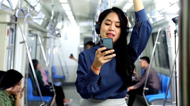 亚洲年轻女性的生活方式，戴着耳机坐地铁上班高峰时间视频素材