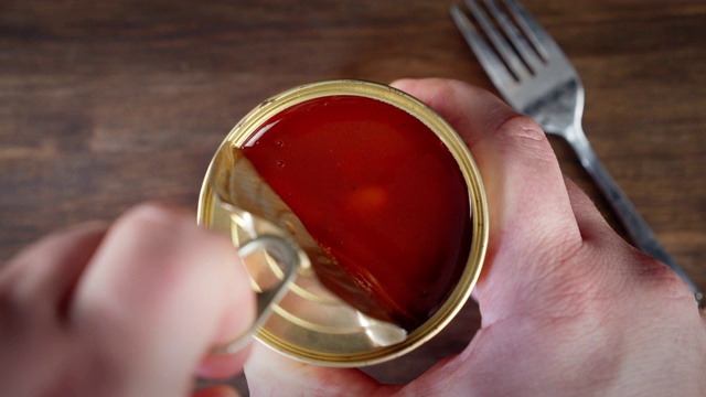 双手打开番茄酱豆罐头。视频下载