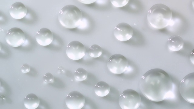 慢动作和超微距拍摄不同大小的水晶清澈的水滴跳跃和溅在浅灰色的表面视频下载