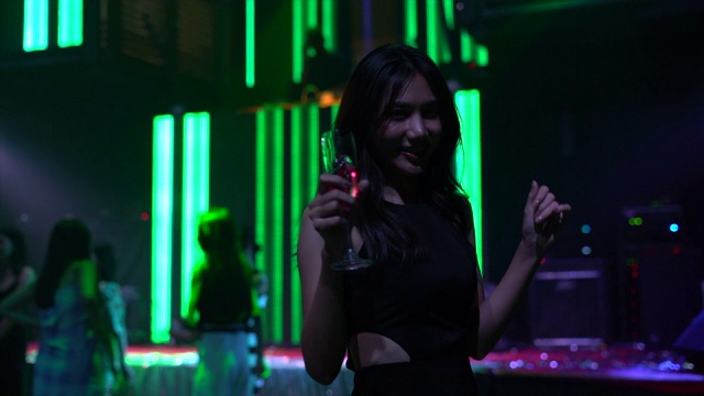 一名亚洲年轻女子在泰国曼谷一家夜总会跳舞时喝酒的4k慢动作视频片段视频下载