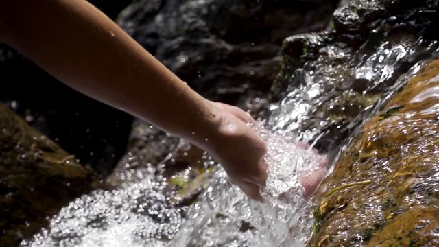 双手触摸小溪中的清澈的水。慢动作视频素材