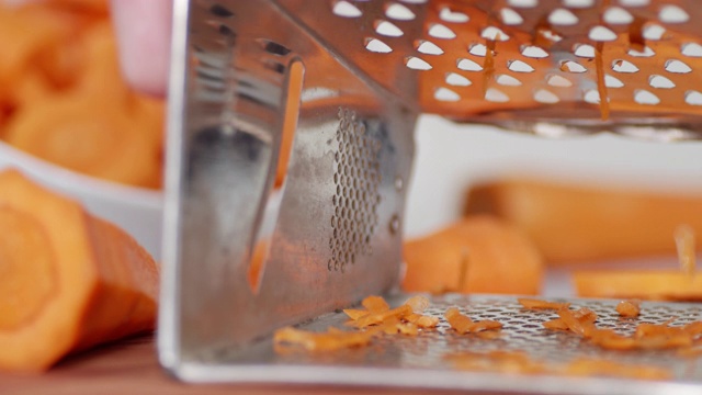 用磨碎器磨碎的新鲜胡萝卜。视频素材