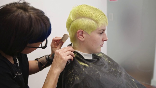 女发型师用电动理发器为年轻女性理发视频下载