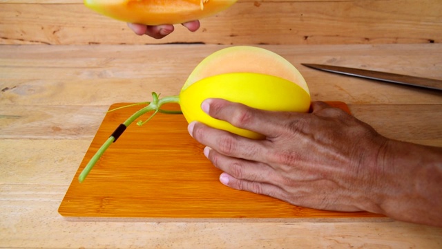 这个人用刀在木板上劈开甜瓜视频素材