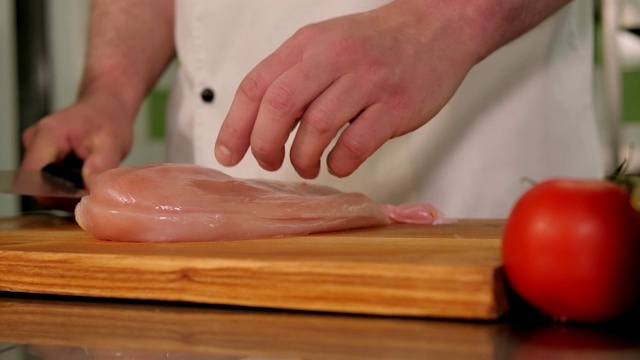 厨师在厨房的切菜板上切鸡柳的特写镜头。视频下载